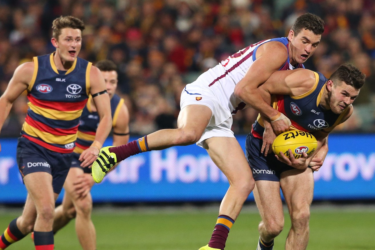 Brad Crouch attempts to break a tackle from Tom Rockliff during the match between the Adelaide Crows and the Brisbane Lions at Adelaide Oval on August 6. Photo: AAP