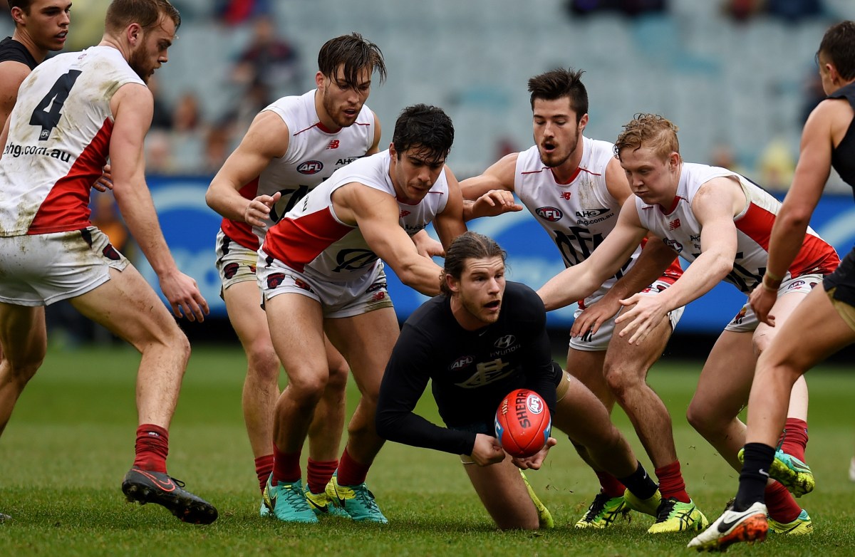 Bryce Gibbs of the Blues passes as he's surrounded by Demons players during their round 22 AFL match between the Carlton Blues and the Melbourne Demons at the MCG in Melbourne, Saturday, Aug. 21, 2016. (AAP Image/Tracey Nearmy) NO ARCHIVING