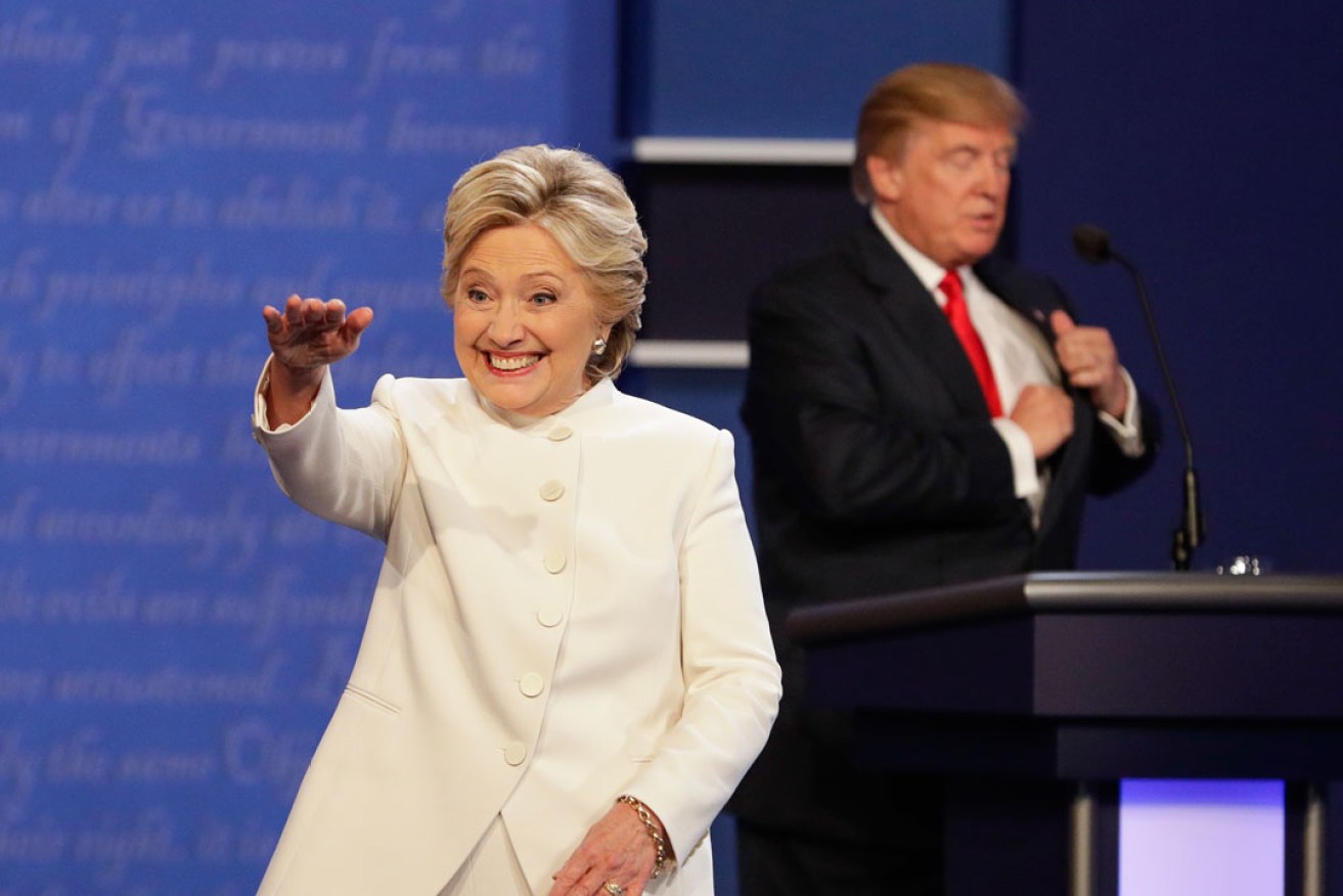 Hillary Clinton waves to the audience as Donald Trump puts away his notes after the presidential debate. Photo: AP