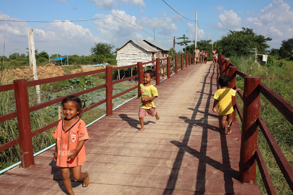 Children run across the bridge at Kom Nor Thmor village. The bridge was provided by Sunrise at a cost of $30,000; before it was built, during the rainy season children could not get to school. Photo: Tony Lewis