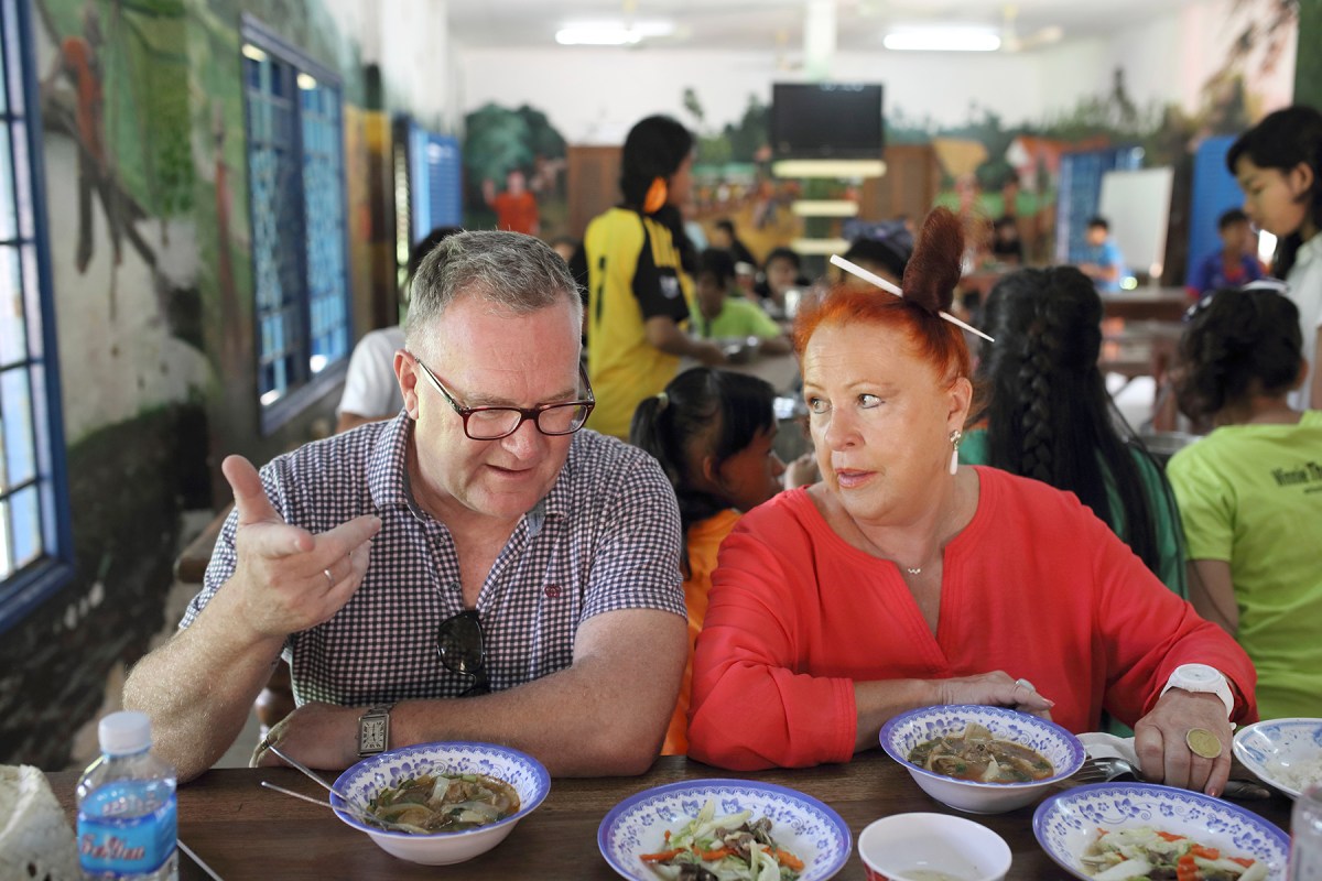Kevin Tutt and Geraldine Cox eat lunch with the orphan children at Sunrise Kandal. Photo: Tony Lewis