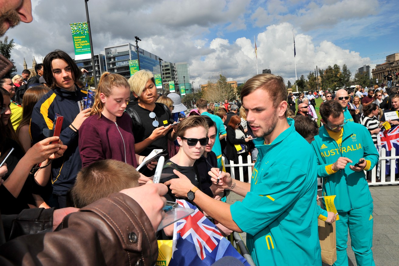 Kyle Chalmers joins other Australian Olympians signing autographs on Victoria Square in a September homecoming parade. Photo: David Mariuz / AAP