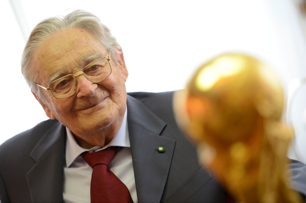 In this photo taken on Thursday, June 3, 2014, Italian goldsmith and sculptor Silvio Gazzaniga poses with his most important work, the FIFA World Cup at GDE Bertoni factory in Paderno Dugnano, near Milan, Italy. Silvio Gazzaniga, the sculptor who created the World Cup trophy, has died. He was 95. Gazzaniga designed and created the World Cup trophy in 1971 after Brazil retained the right to keep the Jules Rimet trophy by winning its third World Cup in 1970. (AP Photo/Giuseppe Aresu)