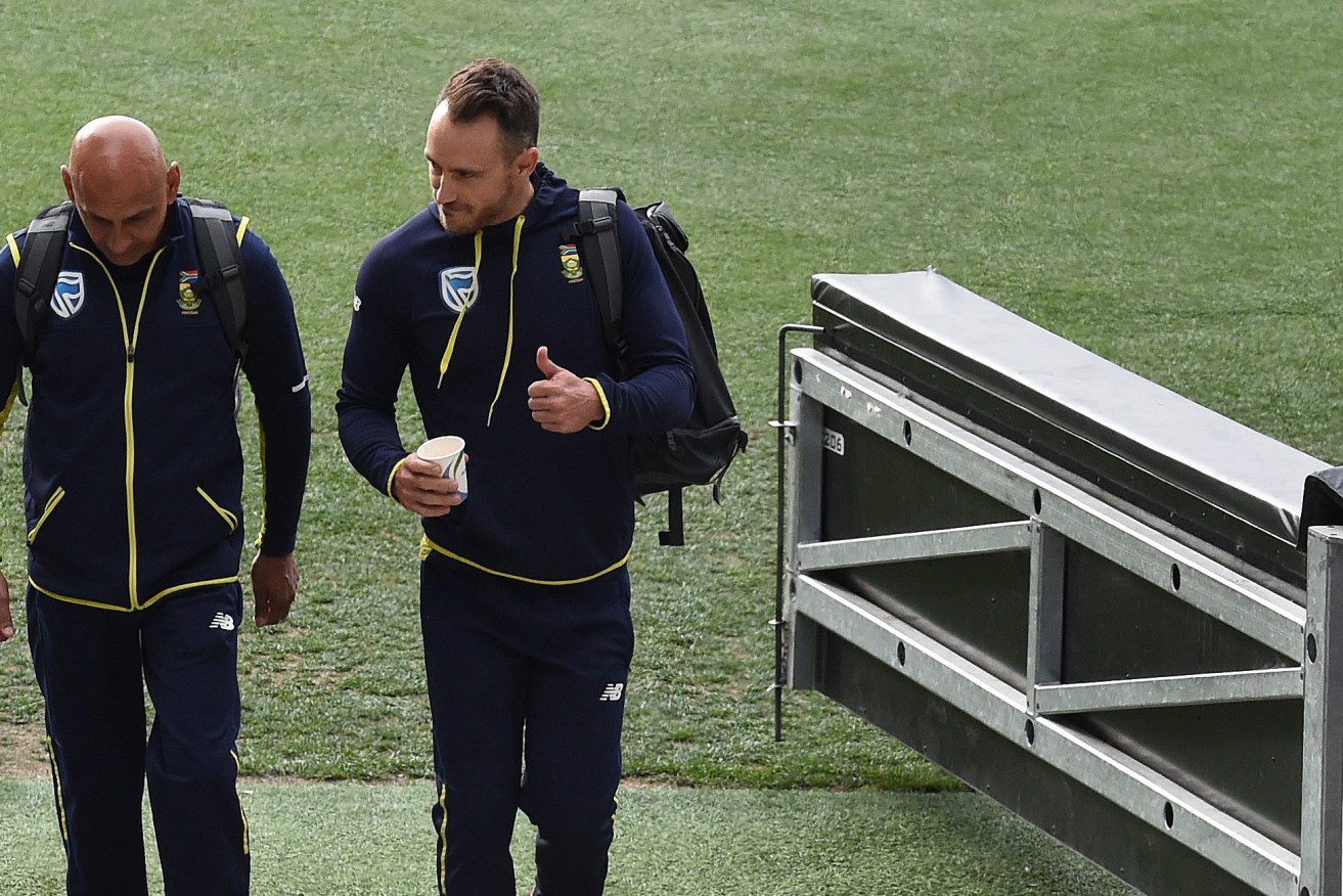 South African captain Faf du Plessis gives the thumbs up as he leaves his ICC hearing at Adelaide Oval yesterday, flanked by the Proteas' head of security Zunaid Wadee, who earlier this week was involved in a scuffle with a journalist. Photo: Dave Hunt / AAP