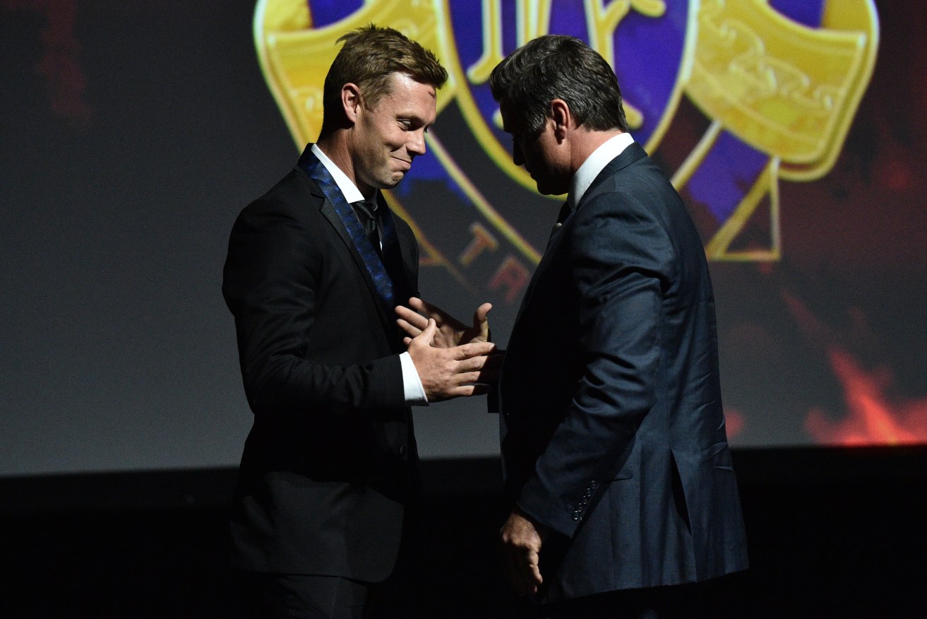 Former Hawthorn player Sam Mitchell is retrospectively awarded the 2012 Brownlow Medal by 1999 Brownlow medalist Shane Crawford. Photo: Julian Smith / AAP