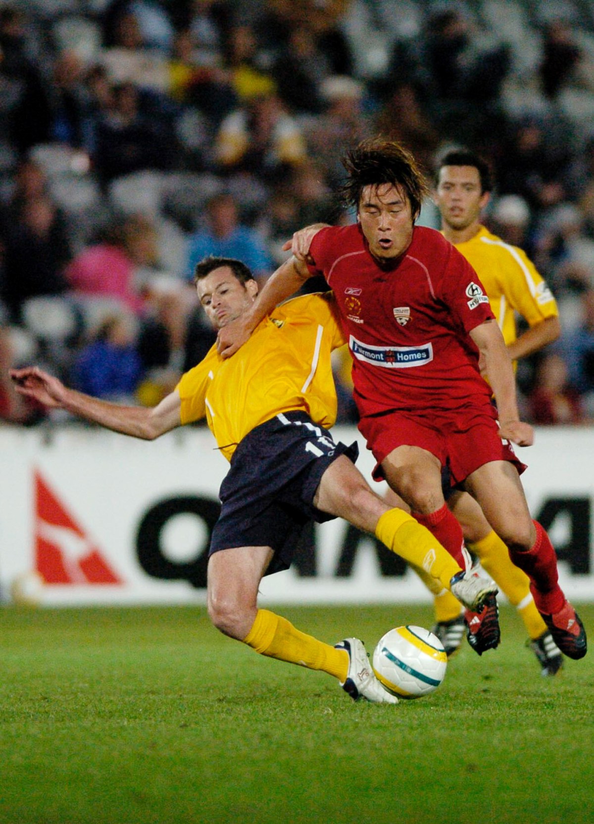 Gosford, May 11, 2005. Damien Brown of the Central Coast Mariners is tackled by Shengqing Qu of Adelaide United during the FIFA Club World Championship Australian Qualifying Tournament at the Central Coast Stadium in Gosford. (AAP Image/Dean Lewins) NO ARCHIVING