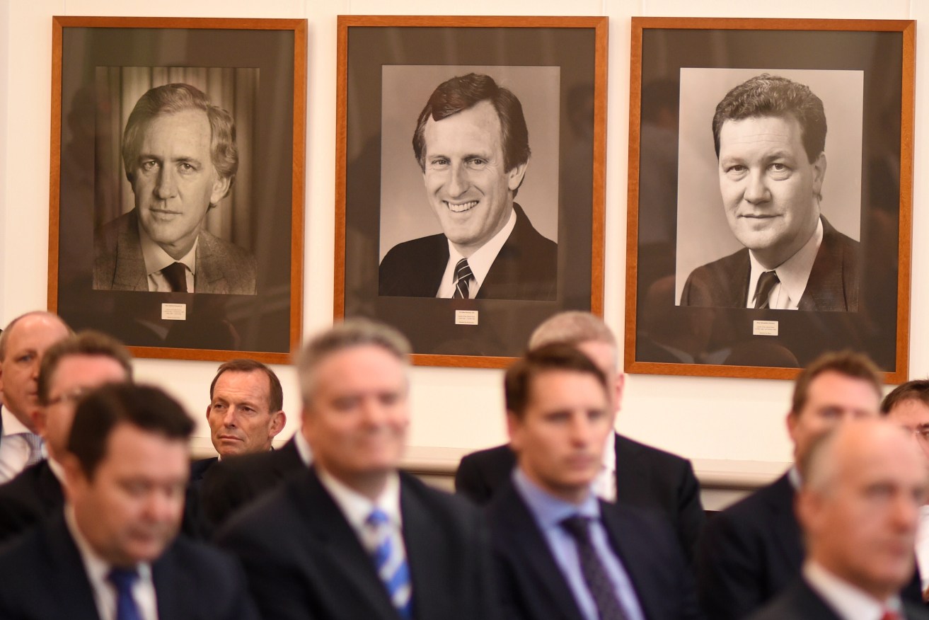 Tony Abbott (rear) listens to Prime Minister Malcolm Turnbull address the party room, beneath the portraits of three former Liberal leaders. Photo: AAP/Lukas Coch
