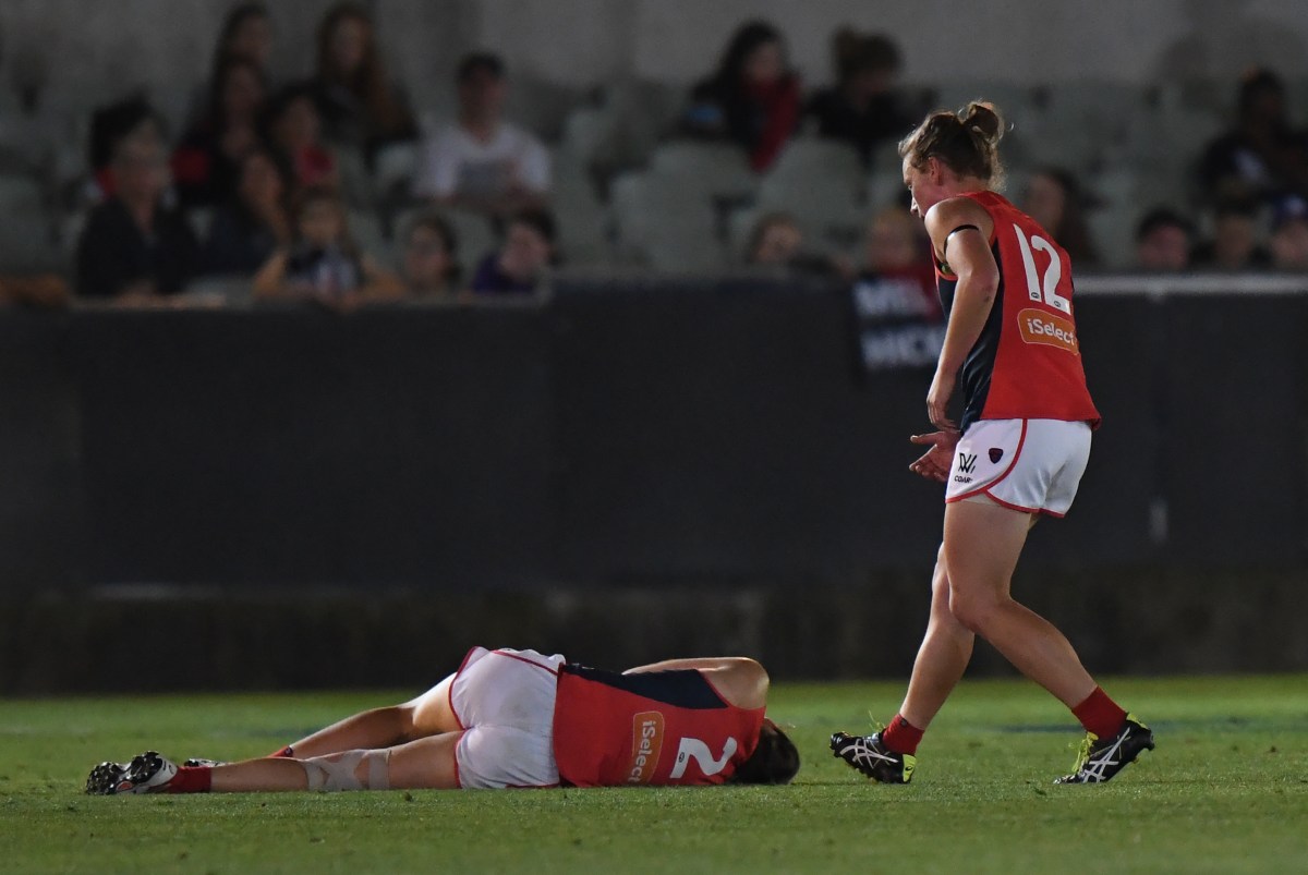 Meg Downie of Melbourne on the ground after being knocked out as Shelly Scott comes in to check on her during their WAFL match at the Ikon Stadium in Melbourne on Saturday, February 11, 2017. (AAP Image/Mal Fairclough) NO ARCHIVING, EDITORIAL USE ONLY