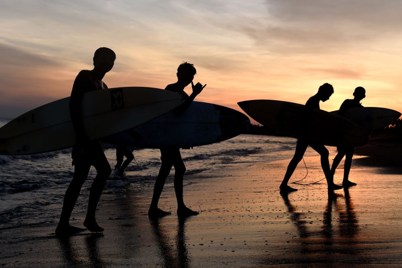Surfers leave the water as the sun sets on Keramas Beach in Bali. Photo: Paul Miller / AAP