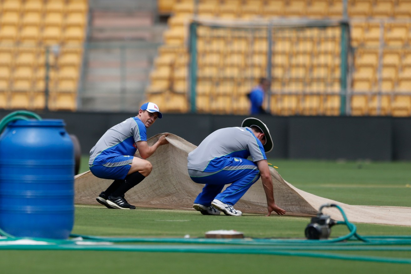 Australia's Steve O'Keefe (left) and Mitchell Marsh lift a cloth to check the pitch area before a training session this week. Photo: Aijaz Rahi / AP