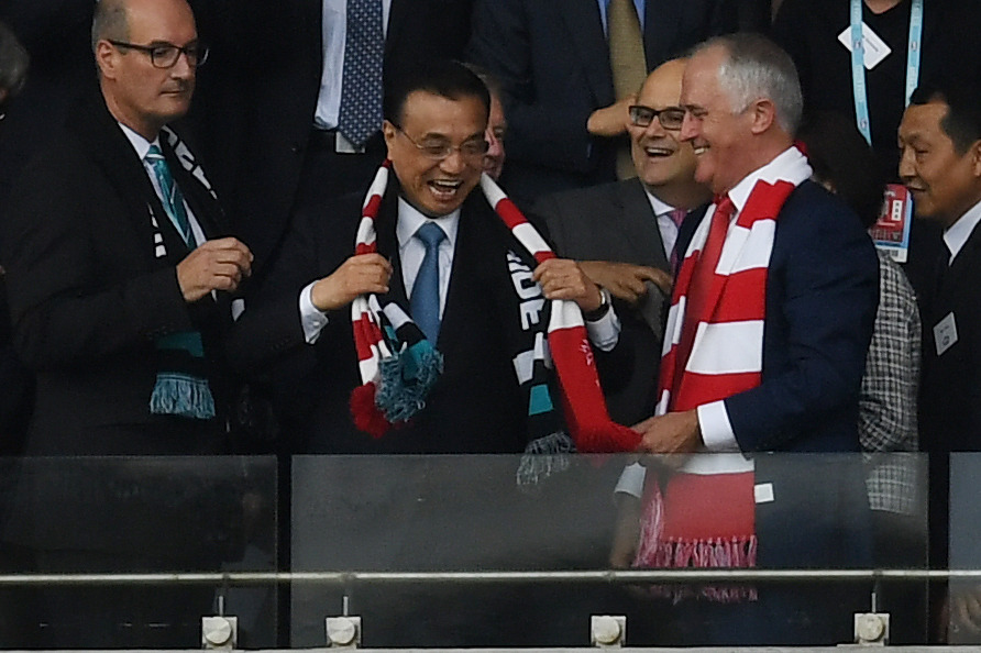 Chinese Premier Li Keqiang puts on a Swans scarf caught by Australian Prime Minister Malcolm Turnbull thrown up to him by a crowd member ahead of the Round 1 AFL match between the Sydney Swans and Port Adelaide at the Sydney Cricket Ground in Sydney, Saturday, March 25, 2017. (AAP Image/Dean Lewins) NO ARCHIVING, EDITORIAL USE ONLY
