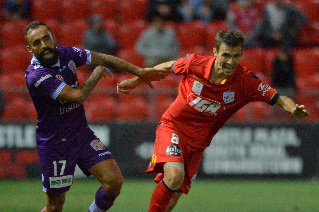 Perth's Diego Castro tussles with Adelaide's Isaias Sanchez during Friday's match. Photo: AAP/David Mariuz
