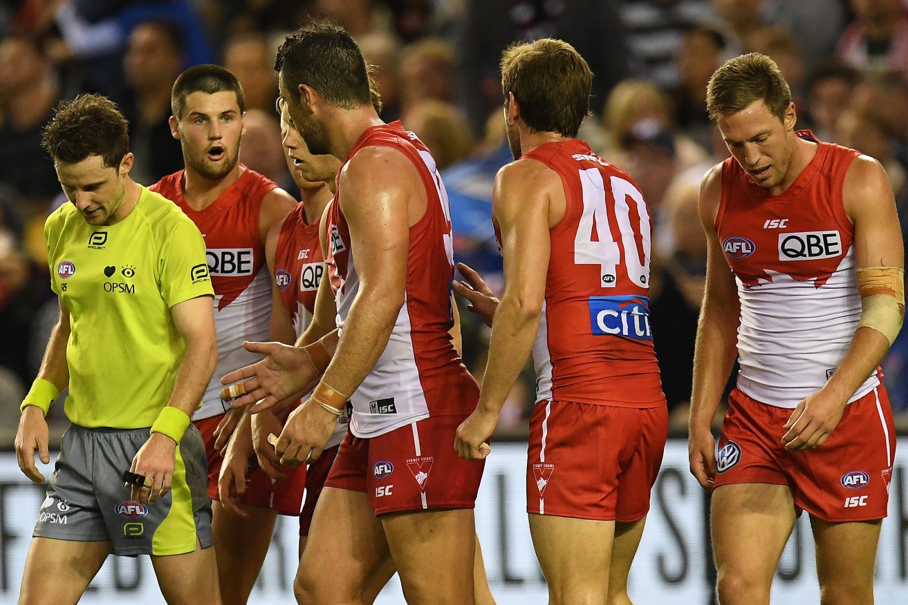 Swans players speak to umpire Brendan Hosking after he awarded a crucial free kick against Callum Mills for a rushed behind on Friday night. Photo: Julian Smith / AAP