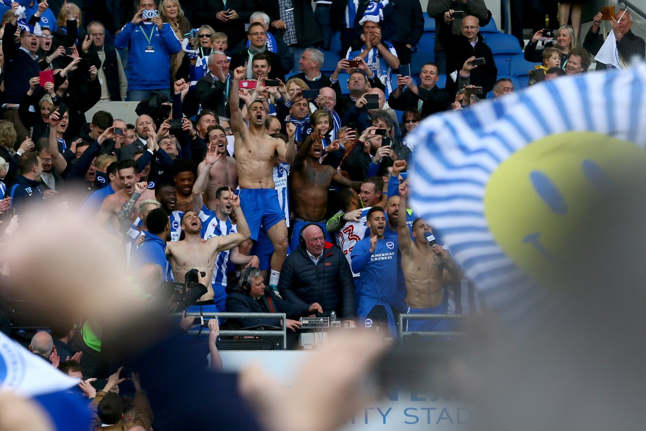 Brighton and Hove Albion players and fans celebrate promotion to the Premier League. Photo: Gareth Fuller/PA Wire