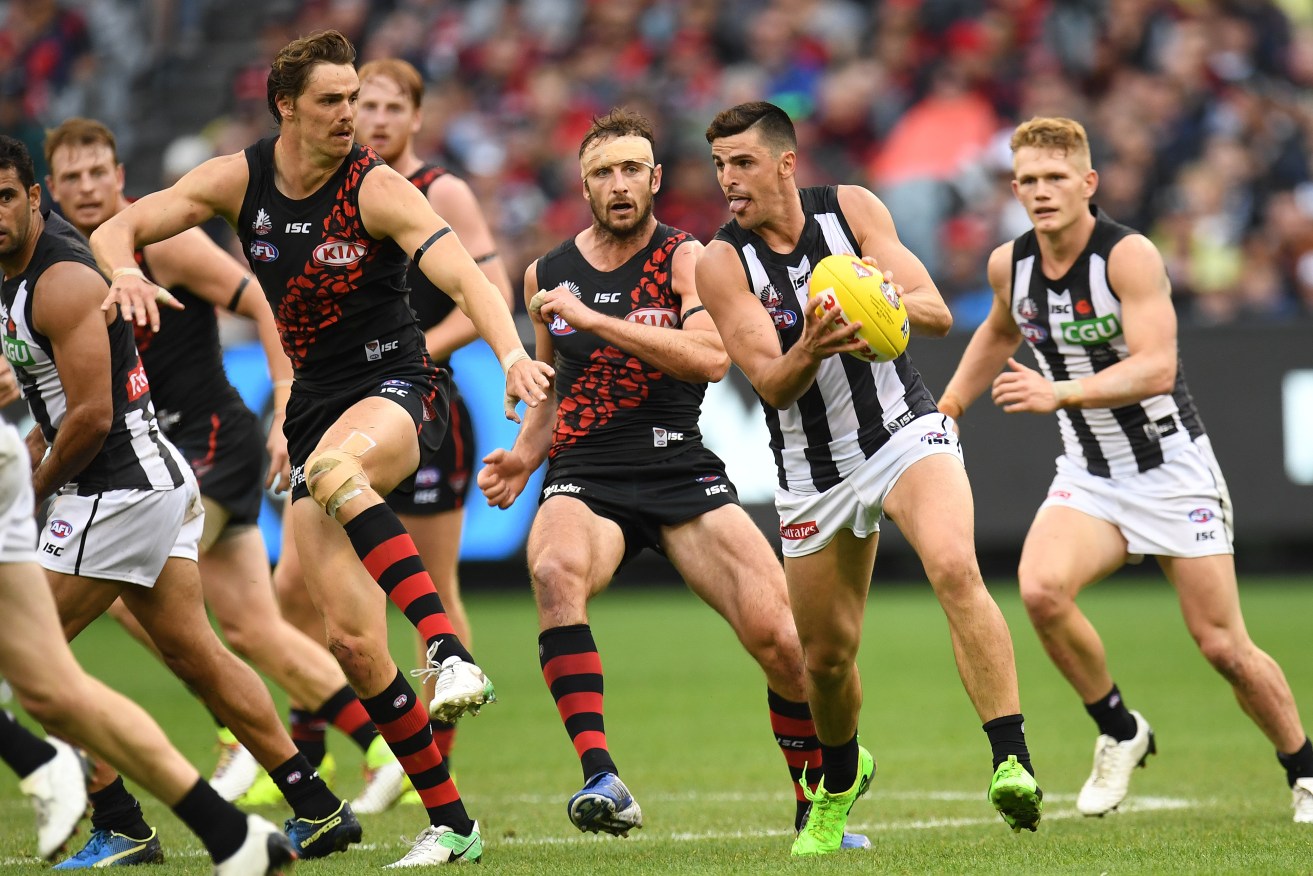 Scott Pendlebury gets one of his 20 touches against Essedon in yesterday's Anzac Day clash. Photo: AAP/Julian Smith