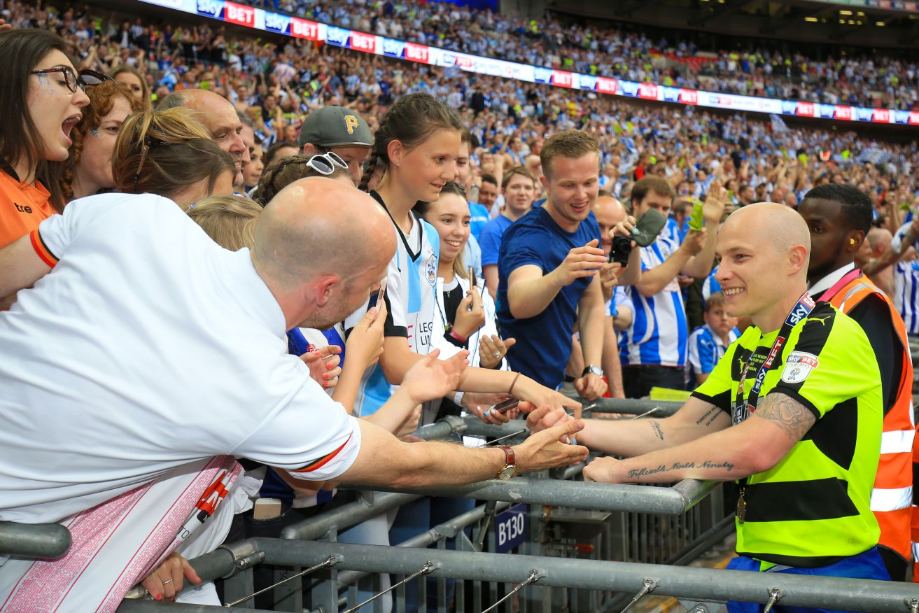 Huddersfield Town's Aaron Mooy celebrates with fans in the stands.