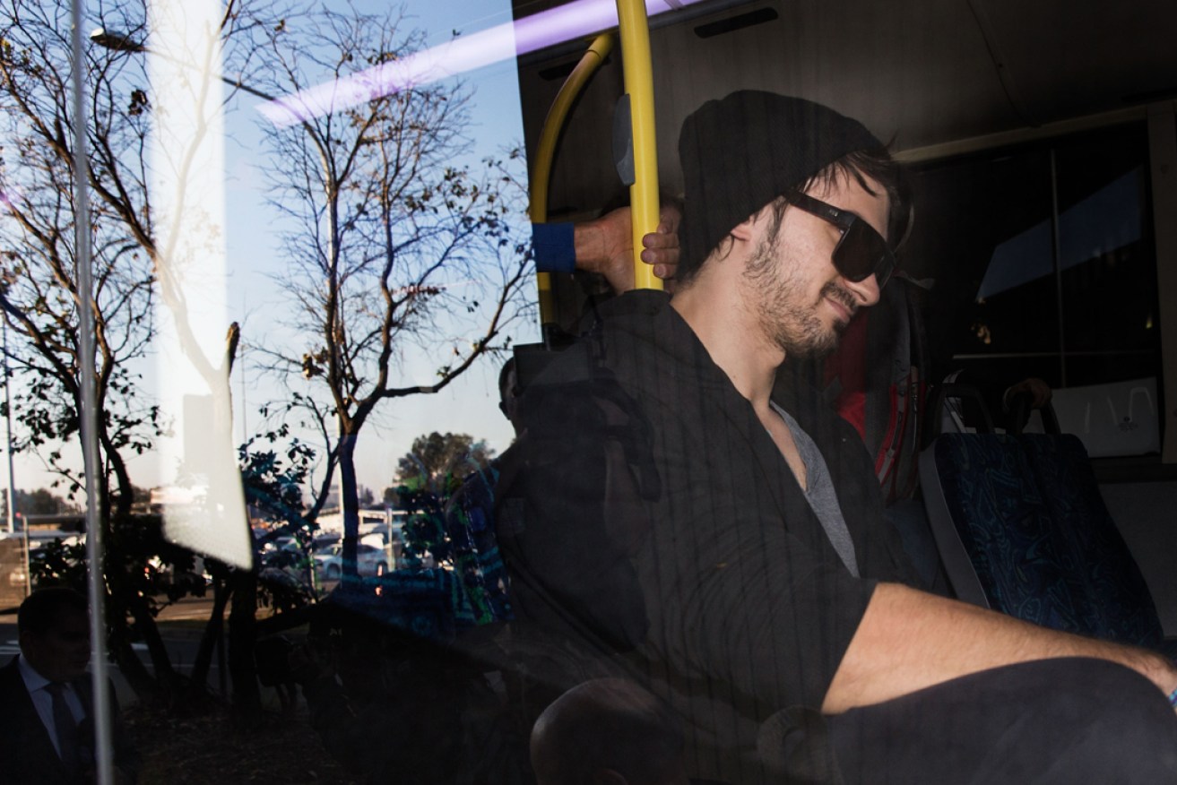 Cassandra Sainsbury's fiancé Scott Broadbridge is escorted to a bus at Sydney Airport. Photo: AAP