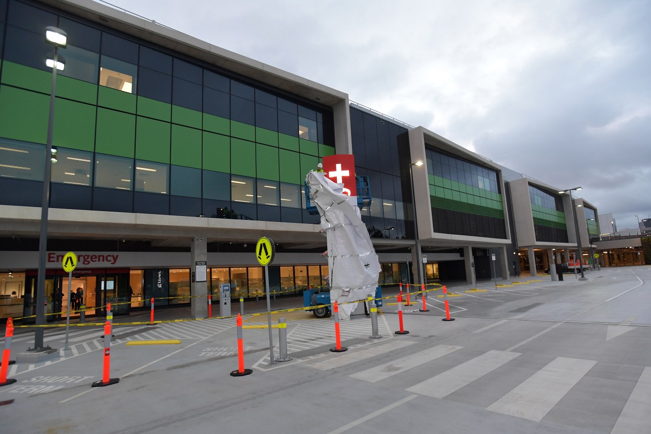 Construction workers unveil the emergency sign during the official opening of the emergency department at the new Royal Adelaide Hospital. Photo: AAP/David Mariuz