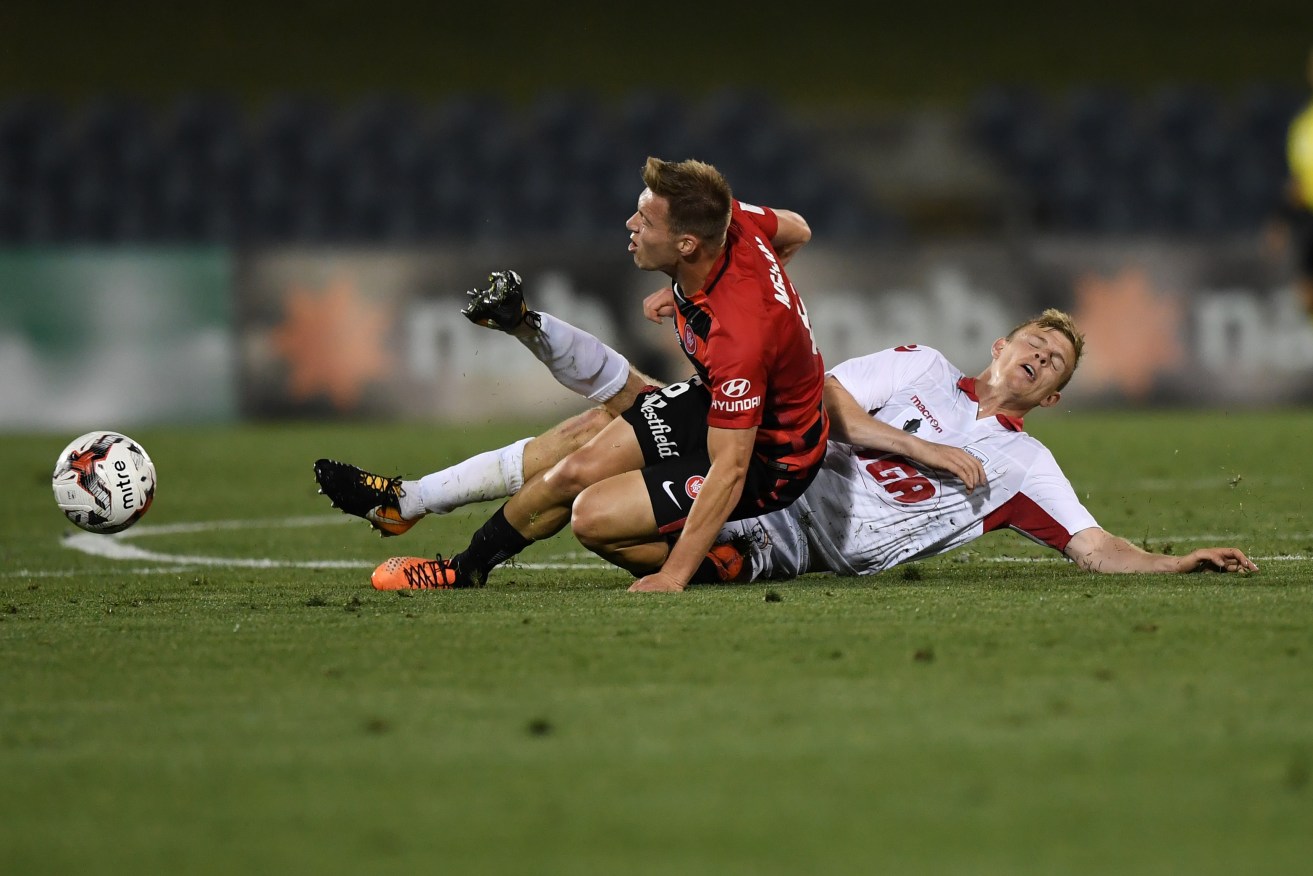 Jordan Elsey is crudely tackled by Wanderer Jacob Melling during last night's FFA Cup semi-final. Photo: David Moir / AAP