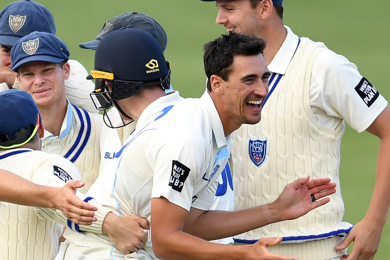 Mitch Starc celebrates with his teammates after taking the wicket of David Moody. Photo: David Moir / AAP