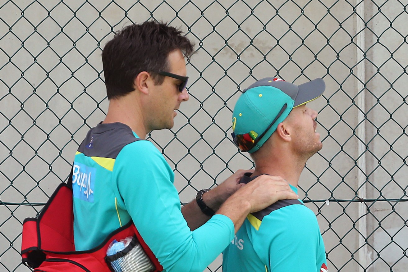 David Warner (right) has his neck looked at by medical staff at training today. Photo: AAP/Jono Searle