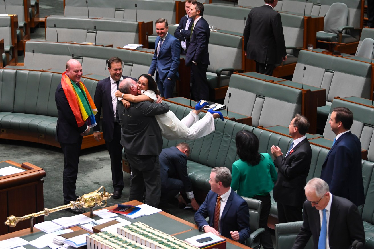 Liberal MP Warren Entsch lifts up Labor MP Linda Burney as they celebrate the passing of the Marriage Amendment Bill in the House of Representatives. Photo: AAP/Lukas Coch
