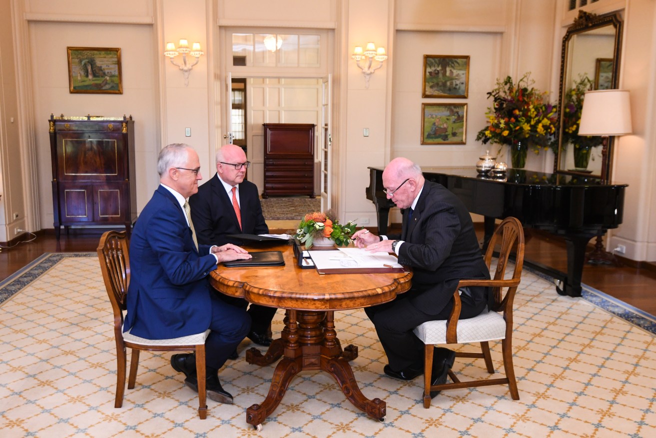 Prime Minister Malcolm Turnbull (left) and Australian Attorney-General George Brandis look on as Governor-General Sir Peter Cosgrove signs the Marriage Amendment Bill. Photo: AAP/Lukas Coch