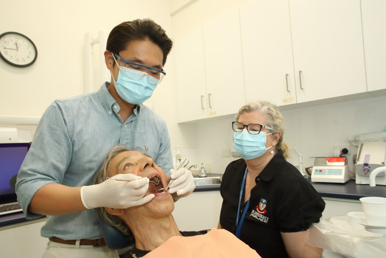 Dentistry student Adrian Wun and dental assistant Amanda Drewer with patient Ted Thornbury, who says the service has improved his confidence. Photo: Tony Lewis / InDaily