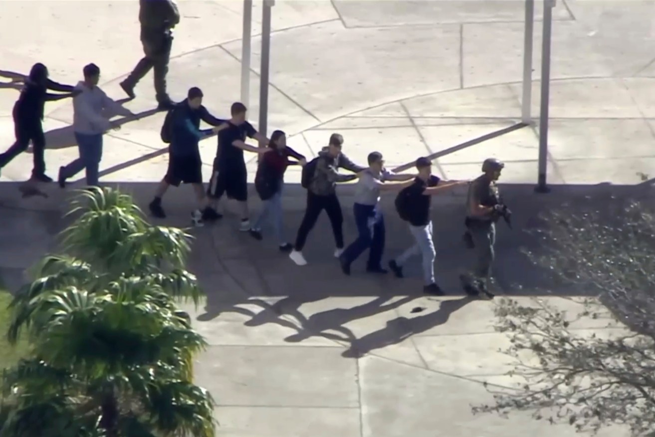 Students from the Marjory Stoneman Douglas High School evacuate the school following the mass shooting. Image: WPLG-TV via AP