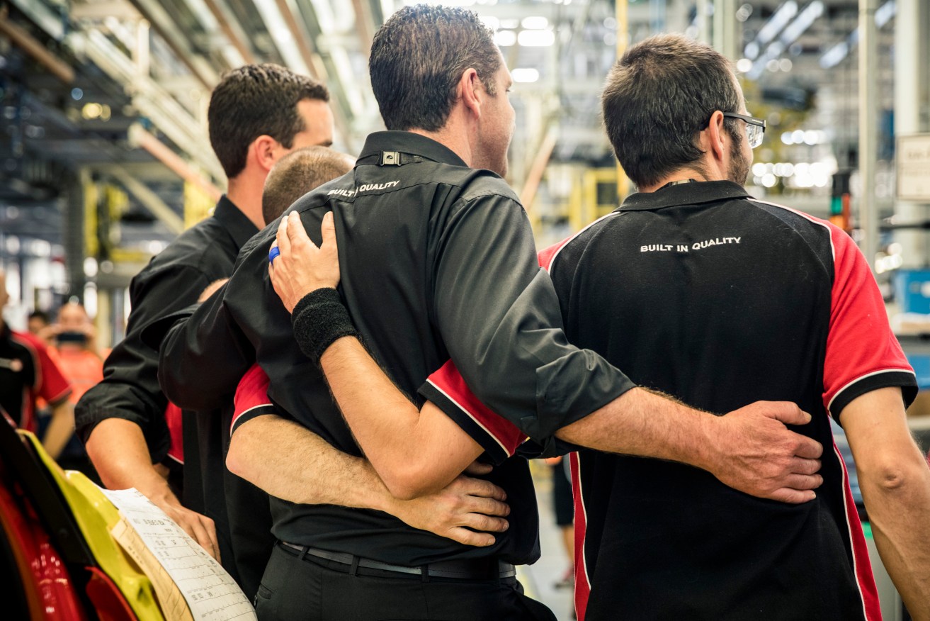 Holden staff embrace as the last vehicle rolls off the production line at Elizabeth. Photo: Supplied by Holden via AAP