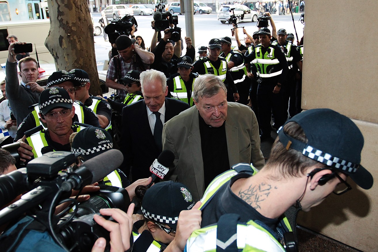 Cardinal Pell arrives at court today surrounded by police officers. Photo: AAP/Stefan Postles