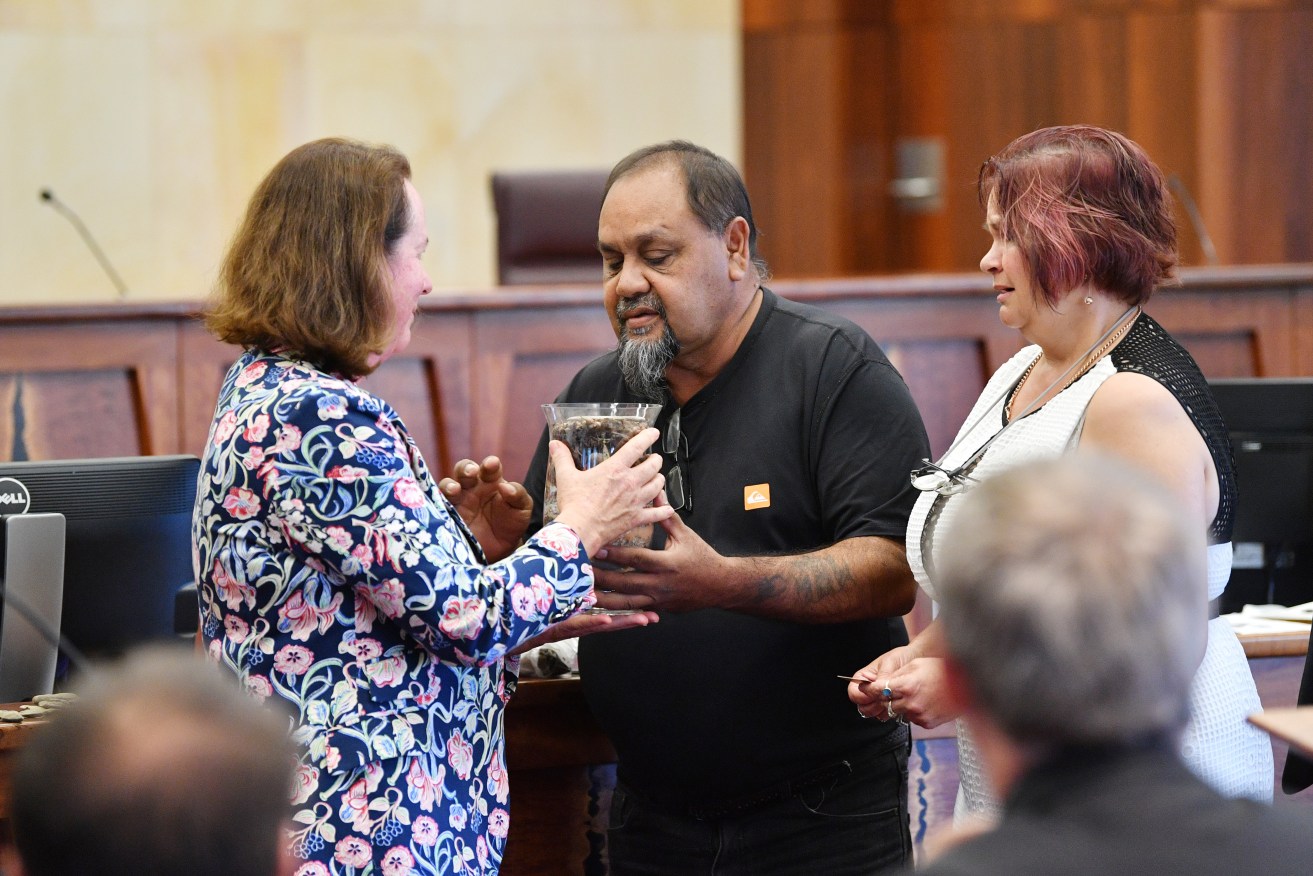 Kaurna representatives Garth Agius (centre) and Suzanne Russell present an urn to Justice Mortimer (left). Photo: AAP/David Mariuz