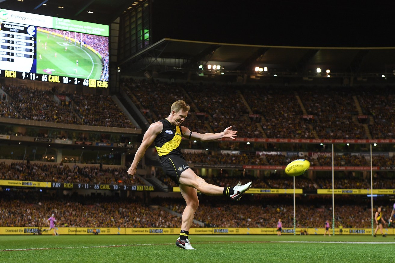 Tiger Jack Riewoldt kicks for goal in front of a record Round 1 crowd last night. Photo: AAP/Julian Smith