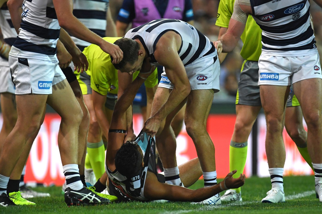 Joel Selwood squares off with a prone Lindsay Thomas after the Port forward's bump on the Cats captain's brother Scott. Photo: Julian Smith / AAP