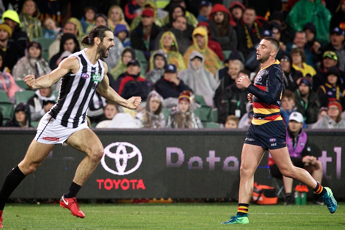 Brodie Grundy celebrates a goal while Rory Atkins ponders the dubious retro appeal of the long-sleeved guernsey. Photo: Michael Errey / InDaily