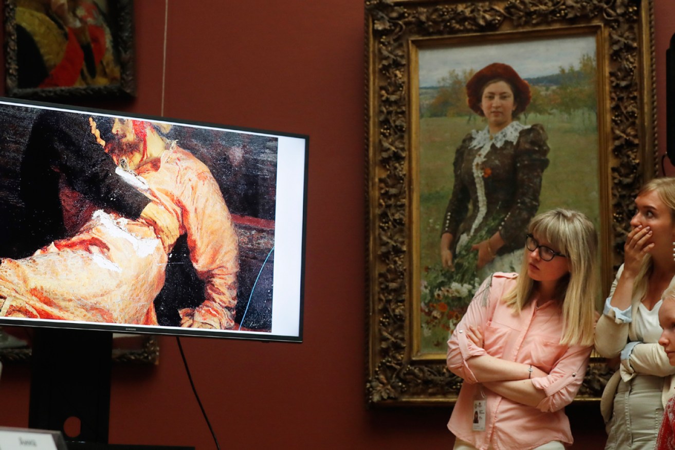 Visitors looks at a monitor showing the damaged Ilya Repin painting at the Tretyakov Gallery. Photo:  EPA