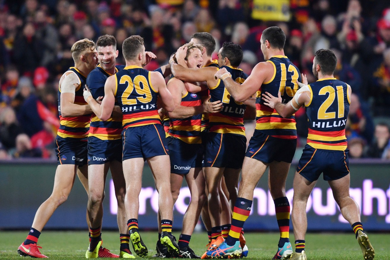 Newly signed Crow Rory Sloane is mobbed by teammates after kicking a crucial goal last night. Photo: AAP/David Mariuz