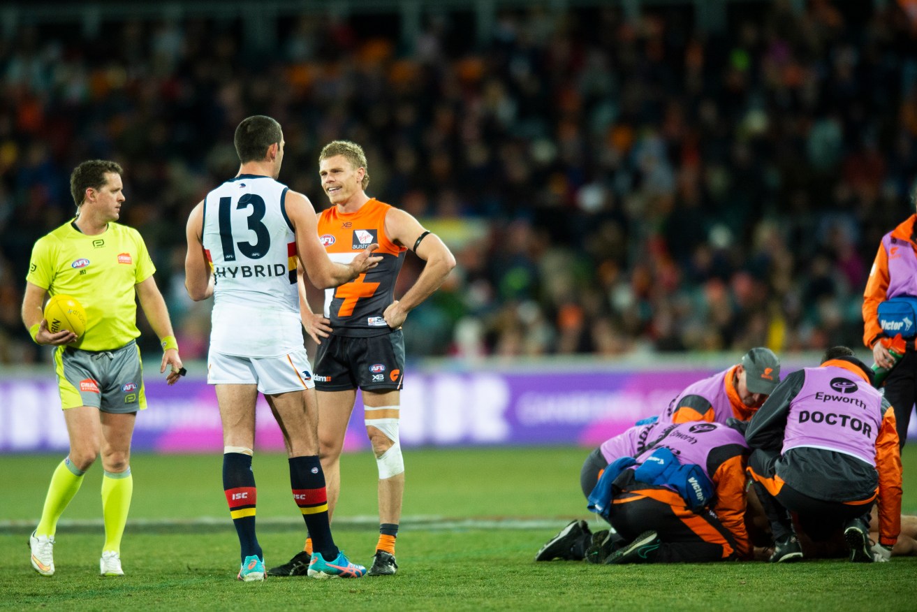 Taylor Walker of the Crows talks with Adam Kennedy while Josh Kelly is treated on the ground. Photo: AAP/Rohan Thomson