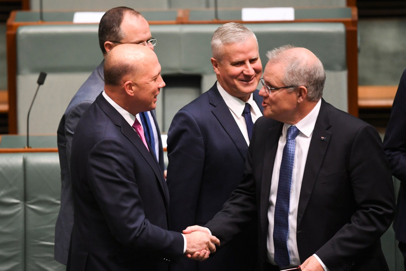 Peter Dutton shakes hands with PM Scott Morrison after a suspension order to move a motion of no confidence was defeated. Photo: AAP