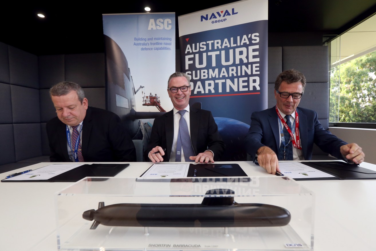 Defence Minister Christopher Pyne (centre) signs the agreement today with Naval Group Australia CEO John Davies (left) and ASC CEO Stuart Whiley. Photo: AAP/Kelly Barnes