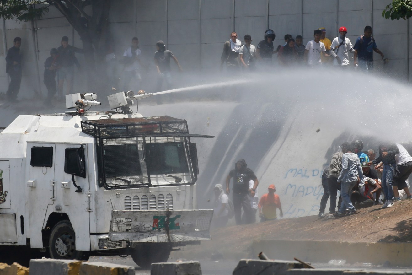 Water cannon target protesters demanding the removal of Venezuela's president Nicolas Maduro. Photo: AP/Ariana Cubillos