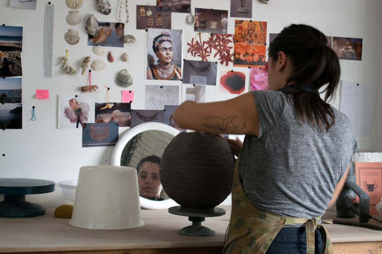 Connie Augoustinos at work, with souvenirs from her artist's residency in Greece on the studio wall. Photo: supplied