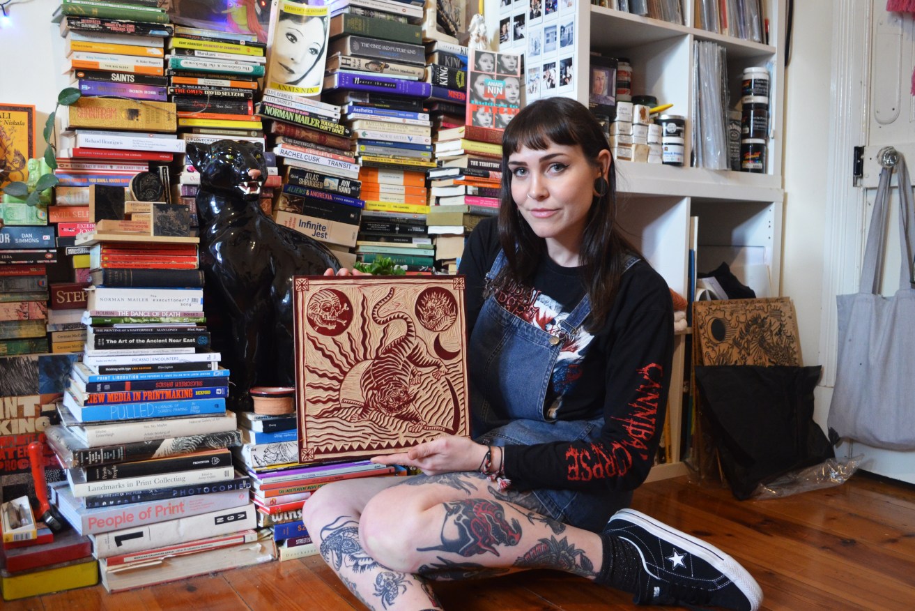 Adelaide artist Kerri Wright in her bedroom holding a woodcut due to be pressed on a flag: "I love it... it's a different way to display your artwork." Photo: Angela Skujins