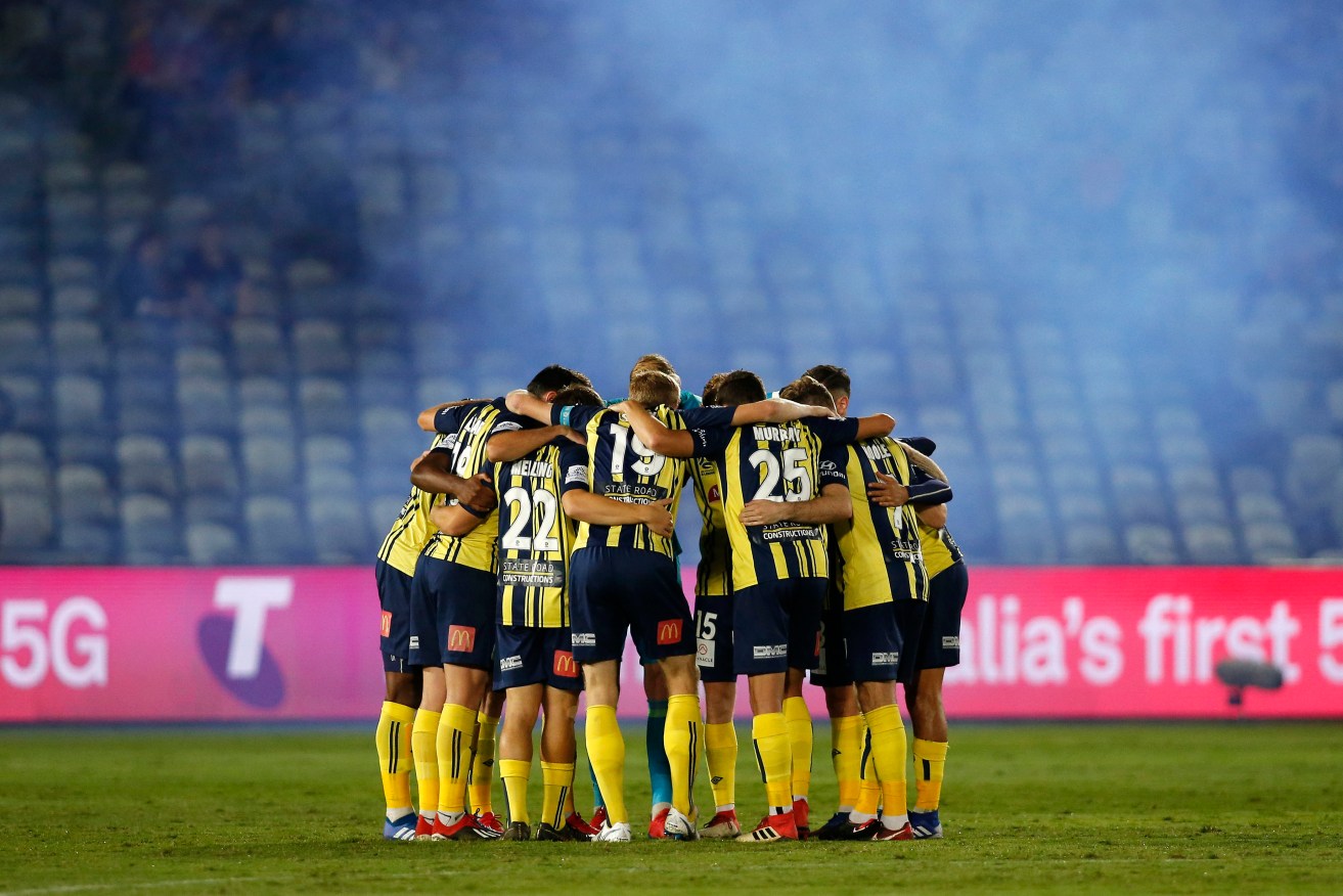 Mariners players huddle in front of a bare stand at their home stadium in Gosford in April. Photo: AAP/Darren Pateman