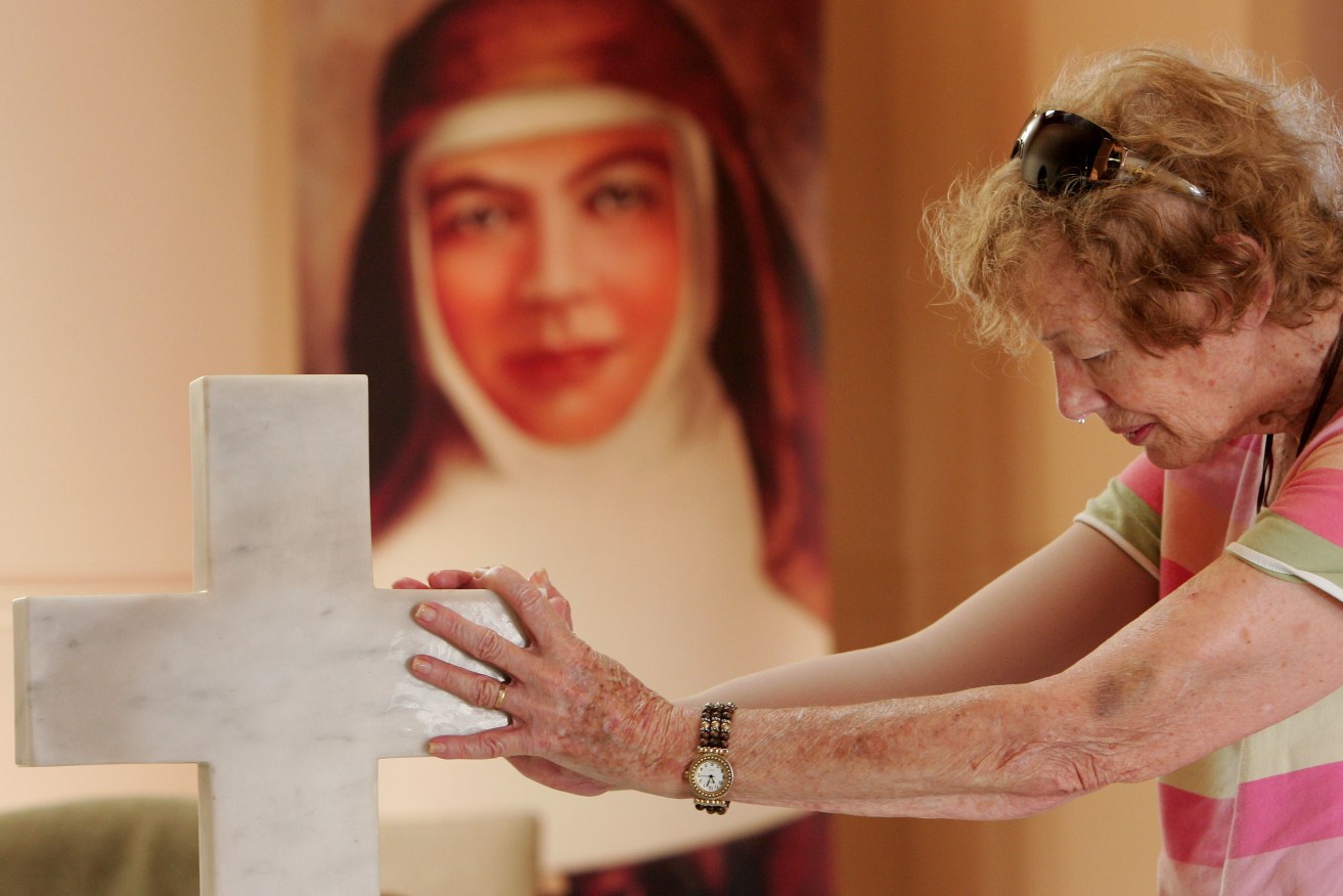A woman prays at the tomb of Mary MacKillop. Photo: AAP/Sergio Dionisio