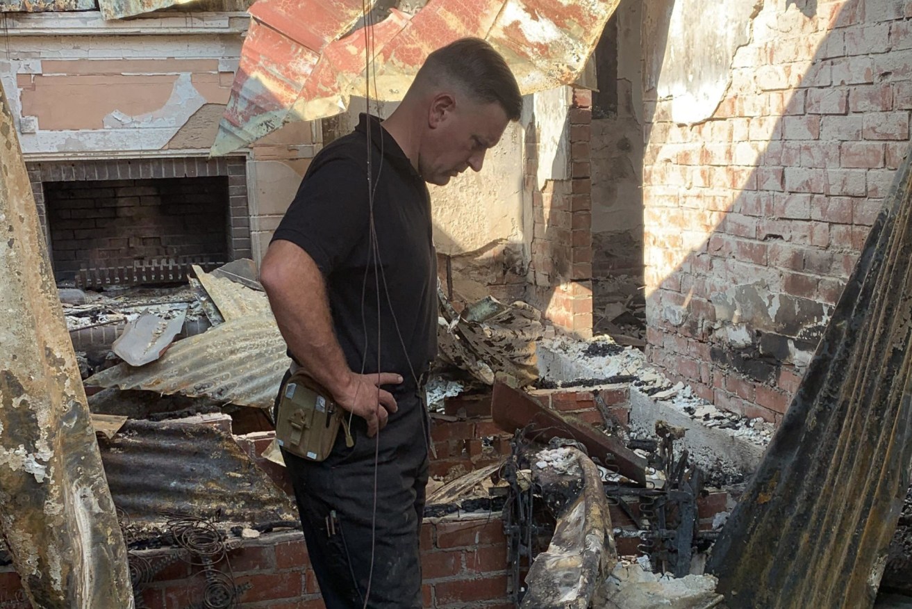 Adam Weinert amid the ruins of his family's Lobethal home, one of 84 houses in the Adelaide Hills destroyed by a December bushfire. Photo: AAP/Supplied