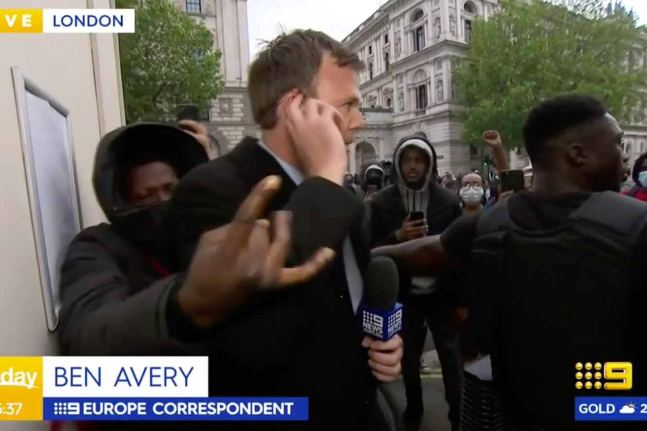 9 reporter Ben Avery, flanked by a security guard, is swamped by protestors in London, live on air.  Photo: AAP Image / Supplied, Nine Network