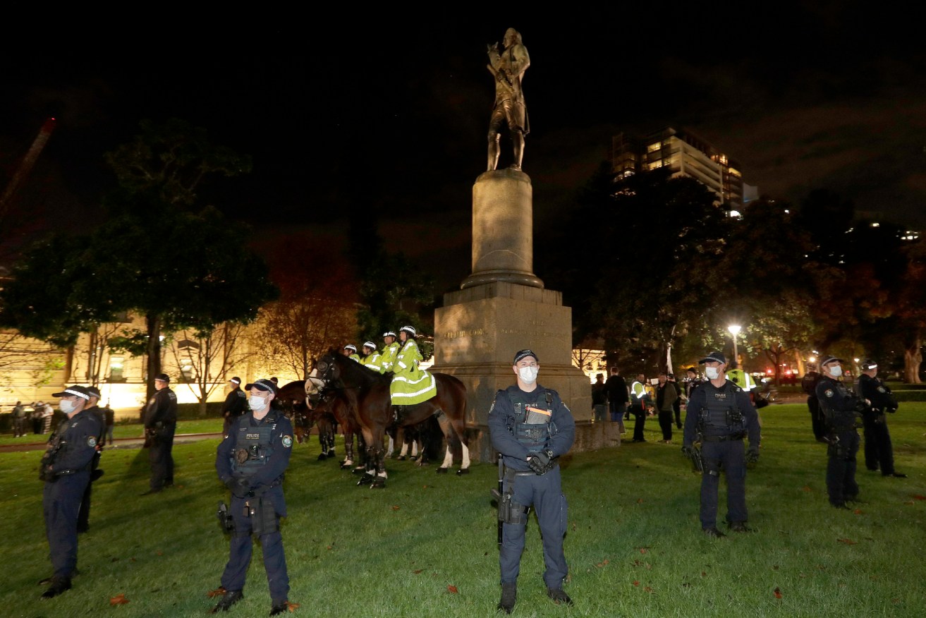 Police guard a statue of British explorer James Cook as protesters gather in Sydney. Photo: AP/Rick Rycroft