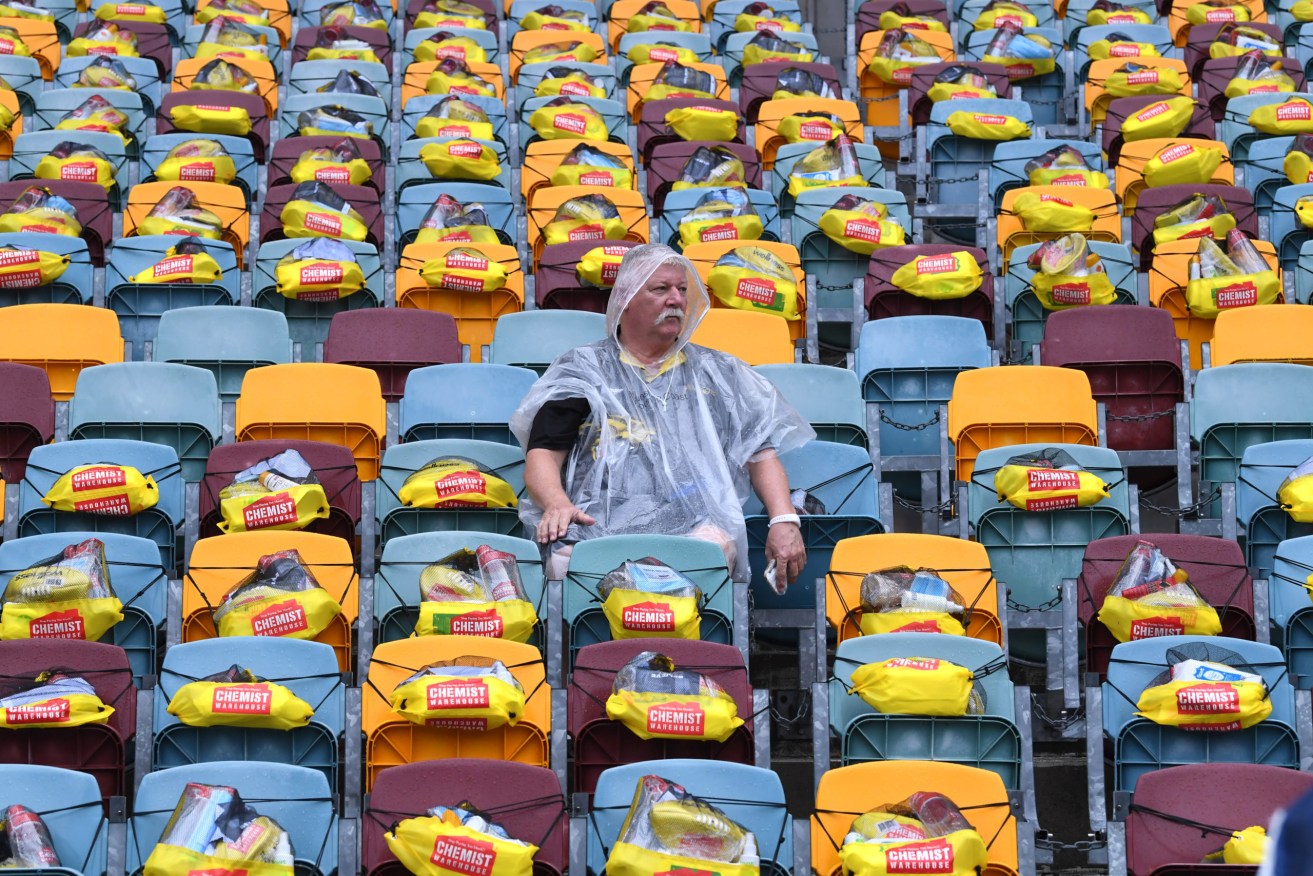 A staffer at Brisbane's Gabba ground places gift packs on seats for the first AFL Grand Final to be played outside Victoria, due to coronavirus. Photo: AAP/Dave Hunt