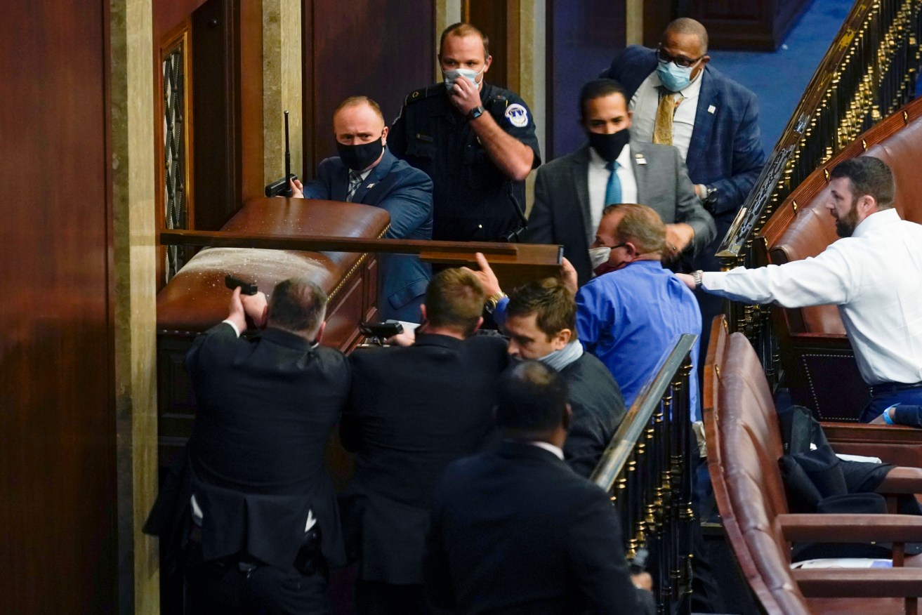 Capitol Police with guns drawn try to stop rioters entering House of Representatives last week. Photo:AP/Andrew Harnik